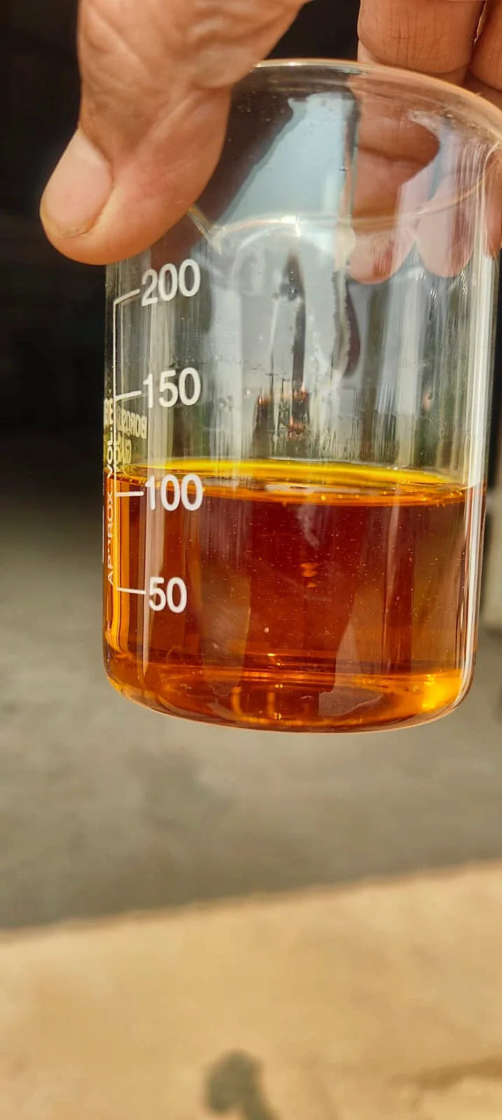 An oil sample held up in a lab beaker